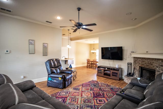 living room featuring a fireplace, crown molding, hardwood / wood-style floors, and ceiling fan with notable chandelier