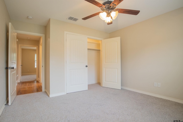 unfurnished bedroom featuring ceiling fan, a closet, and light colored carpet