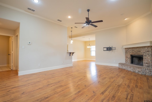 unfurnished living room featuring a brick fireplace, light hardwood / wood-style flooring, ceiling fan, and ornamental molding