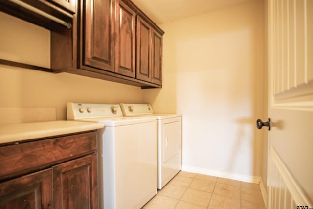 laundry room featuring washer and clothes dryer, light tile patterned floors, and cabinets