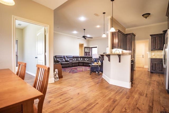 kitchen featuring light stone countertops, a breakfast bar, ceiling fan, crown molding, and hardwood / wood-style floors