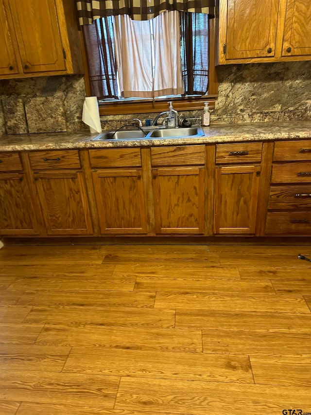 kitchen with backsplash, sink, and light hardwood / wood-style flooring