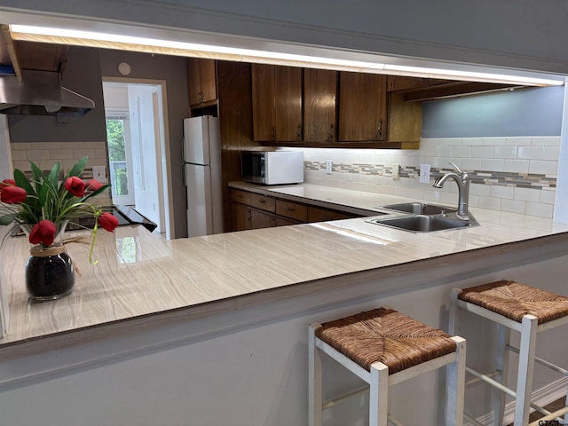 20868 Bay Shore Dr, Flint, TX 75762 - kitchen with stainless steel microwave, freestanding refrigerator, decorative backsplash, dark brown cabinets, and light countertops