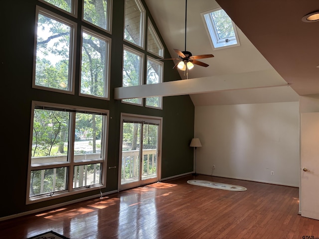 20868 Bay Shore Dr, Flint, TX 75762 - unfurnished living room featuring a towering ceiling, wood finished floors, a skylight, and a ceiling fan