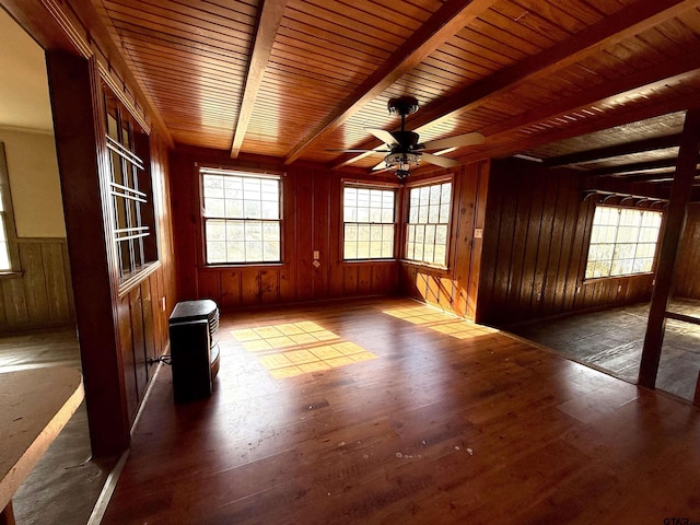 unfurnished room with wood walls, dark wood-type flooring, beam ceiling, and ceiling fan