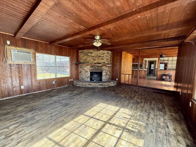 unfurnished living room featuring ceiling fan, beam ceiling, a fireplace, a wall mounted air conditioner, and wooden walls