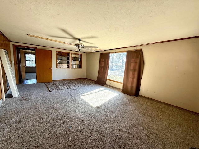 carpeted spare room with ceiling fan, a healthy amount of sunlight, crown molding, and a textured ceiling