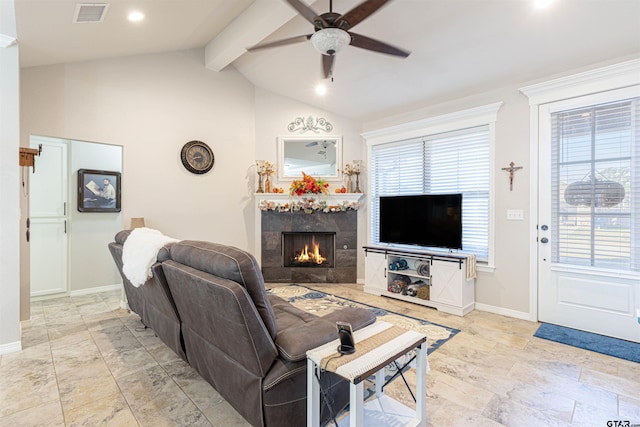 living room featuring lofted ceiling with beams, a tile fireplace, and ceiling fan