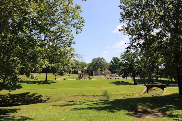 view of property's community featuring playground community and a yard