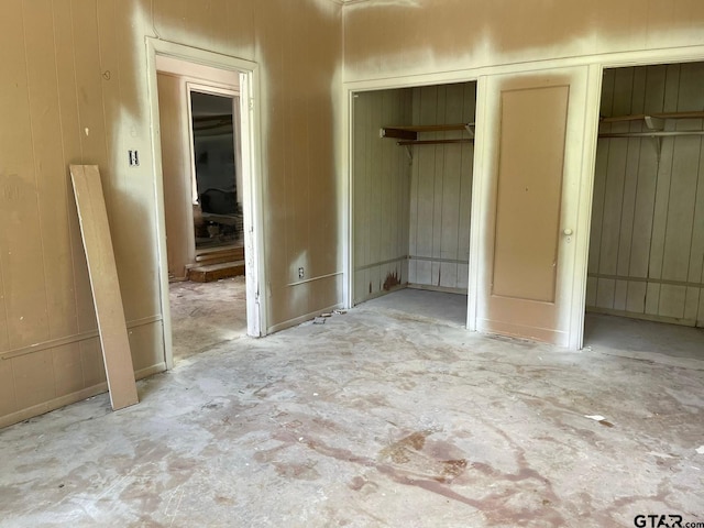 unfurnished bedroom featuring concrete flooring and wooden walls