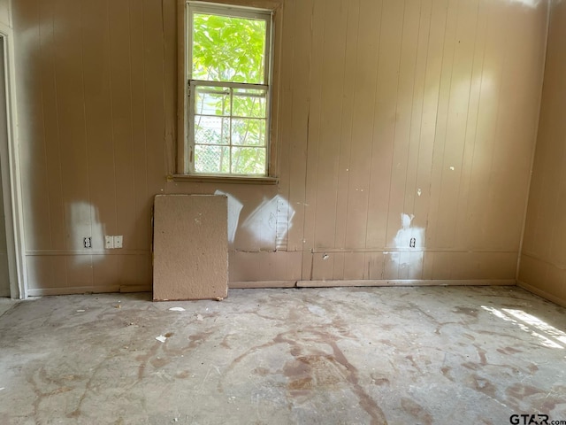 spare room with wood walls and unfinished concrete floors