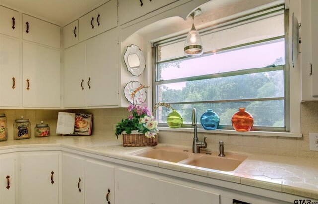 114 Mockingbird, Mount Pleasant, TX 75455 - kitchen featuring a sink, light countertops, tasteful backsplash, and white cabinetry