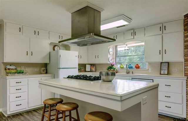 114 Mockingbird, Mount Pleasant, TX 75455 - kitchen featuring freestanding refrigerator, island range hood, stainless steel gas stovetop, tasteful backsplash, and light countertops