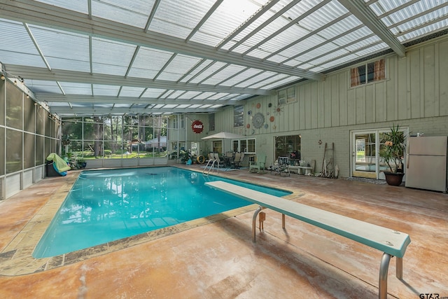 view of pool with a diving board, glass enclosure, and a patio