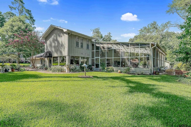 rear view of property with a lawn and glass enclosure