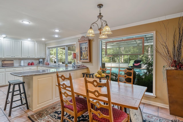 dining area featuring a chandelier, sink, crown molding, and light tile patterned floors