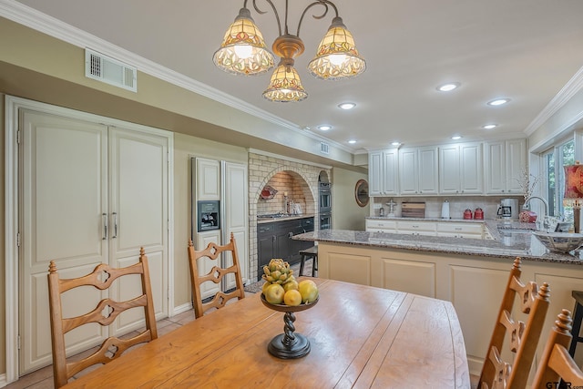 dining area with sink, light tile patterned floors, and crown molding