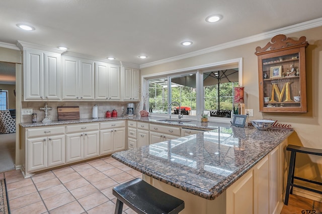 kitchen with white cabinets, kitchen peninsula, crown molding, and a kitchen bar