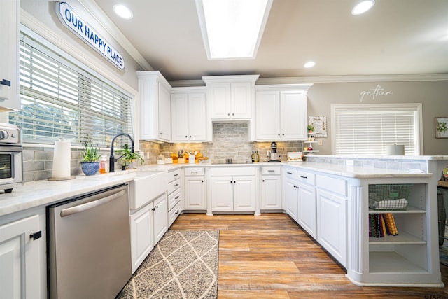 kitchen with backsplash, crown molding, stainless steel dishwasher, light wood-type flooring, and white cabinetry