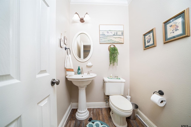 bathroom with wood-type flooring, ornamental molding, and toilet