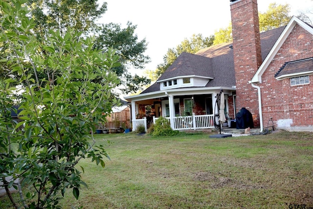 rear view of property featuring a lawn and covered porch