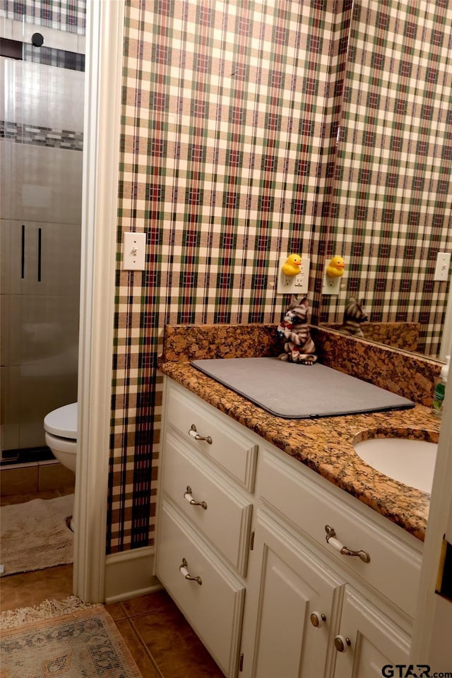 bathroom with tile patterned flooring, vanity, toilet, and walk in shower