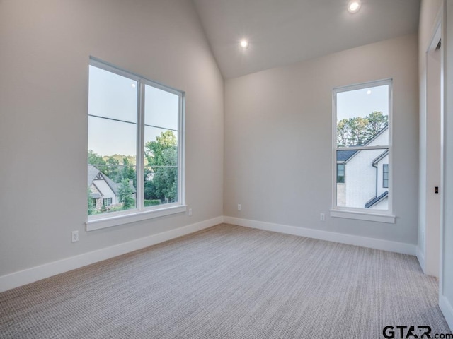 carpeted empty room with a wealth of natural light and vaulted ceiling