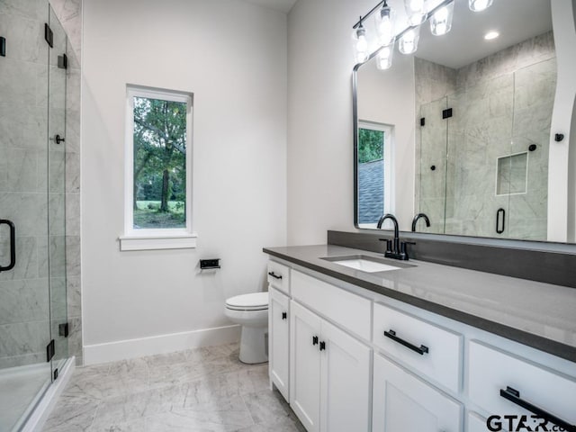 bathroom with vanity, a shower with shower door, a healthy amount of sunlight, and toilet