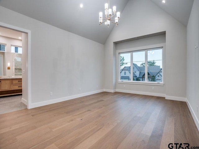 unfurnished room featuring high vaulted ceiling, light hardwood / wood-style flooring, and an inviting chandelier