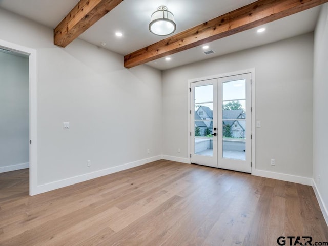 empty room with beamed ceiling, light wood-type flooring, and french doors