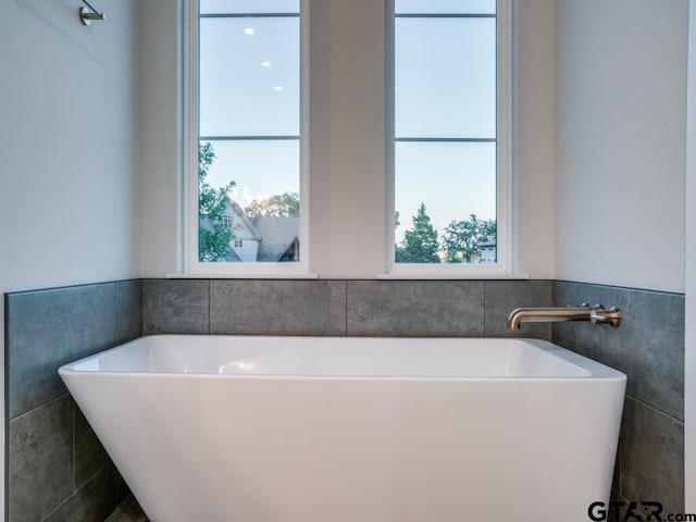 bathroom featuring a washtub and tile walls