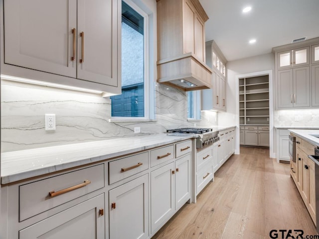 kitchen with white cabinets, stainless steel gas stovetop, light wood-type flooring, and decorative backsplash