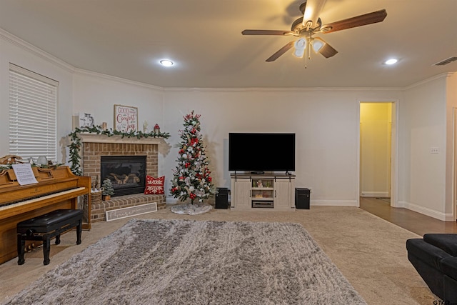 living room featuring carpet flooring, ceiling fan, ornamental molding, and a brick fireplace