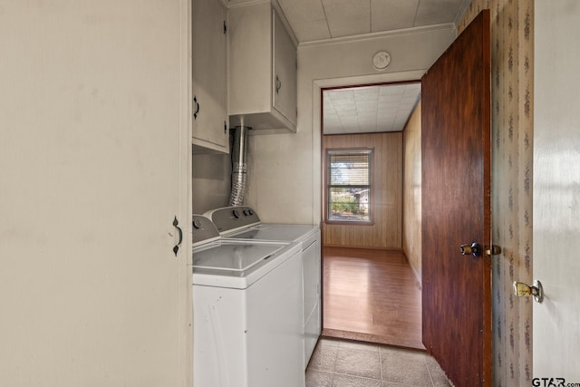 laundry area featuring cabinets, wood walls, light wood-type flooring, and washer and clothes dryer