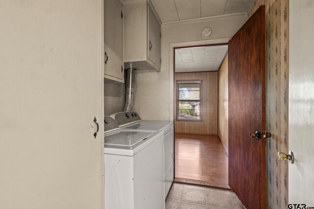 laundry area featuring cabinets, wood walls, light wood-type flooring, and washer and clothes dryer