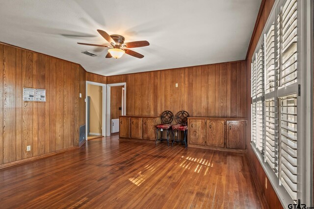 spare room with wood walls, dark hardwood / wood-style floors, and ceiling fan