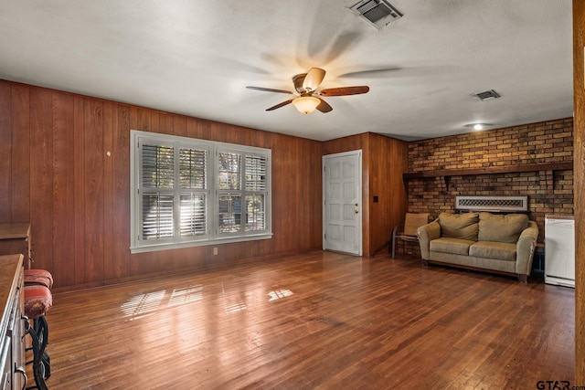 302 Smith St, Naples, TX 75568 - living area with a ceiling fan, wooden walls, wood finished floors, and a brick fireplace