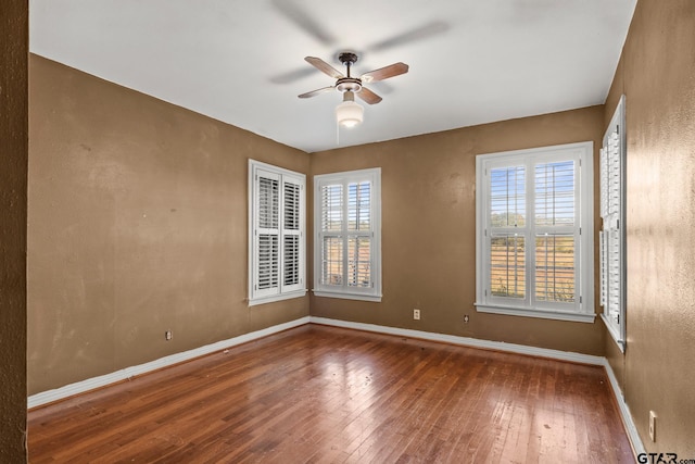 empty room featuring hardwood / wood-style floors, ceiling fan, and a healthy amount of sunlight