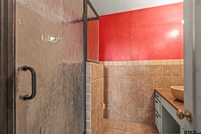 bathroom with vanity, tile patterned floors, an enclosed shower, and tile walls