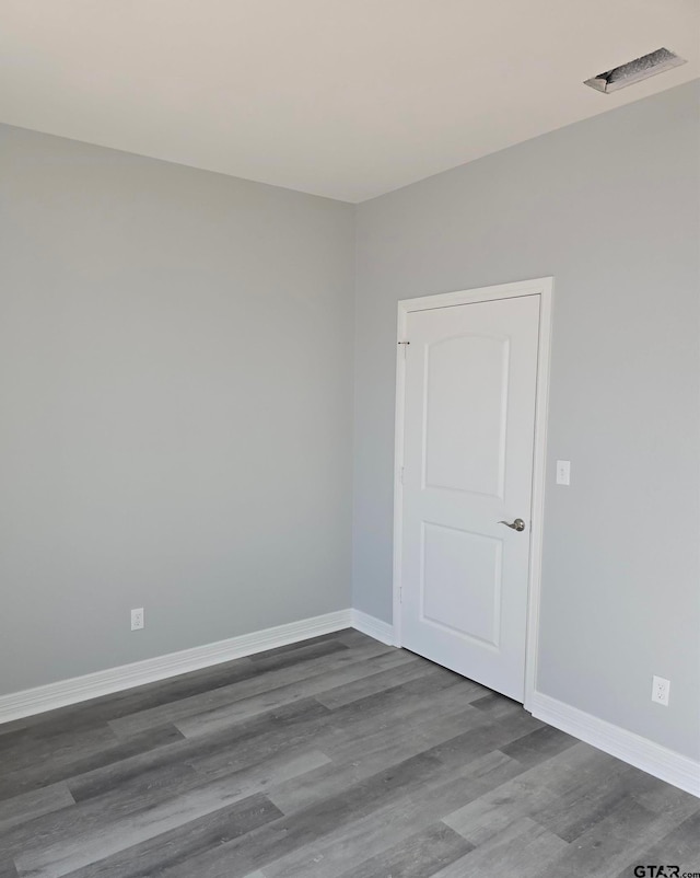 spare room with visible vents, baseboards, and wood finished floors
