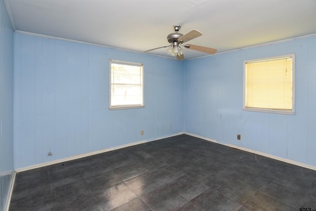 empty room with ornamental molding, wood walls, and ceiling fan