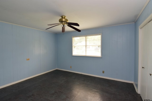 spare room featuring wooden walls, ceiling fan, and crown molding