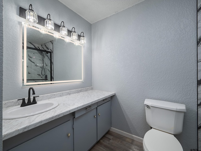 bathroom with a shower with shower door, toilet, a textured ceiling, hardwood / wood-style flooring, and vanity