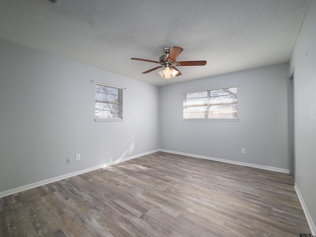 spare room with ceiling fan, plenty of natural light, a textured ceiling, and wood-type flooring