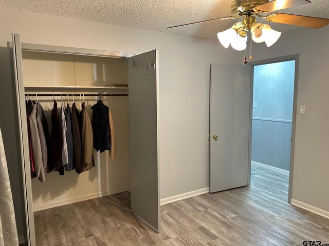 unfurnished bedroom with a closet, a textured ceiling, dark hardwood / wood-style floors, and ceiling fan