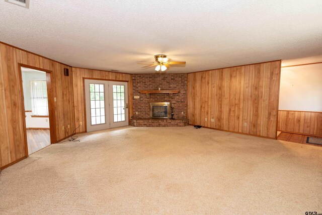 unfurnished living room featuring wood walls, ceiling fan, and light colored carpet