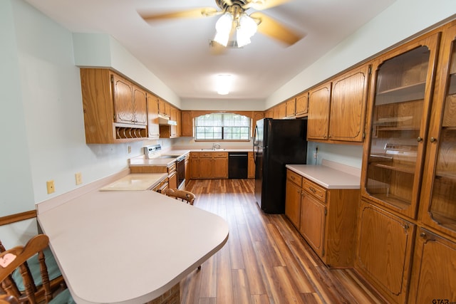 kitchen with kitchen peninsula, black appliances, hardwood / wood-style flooring, and sink