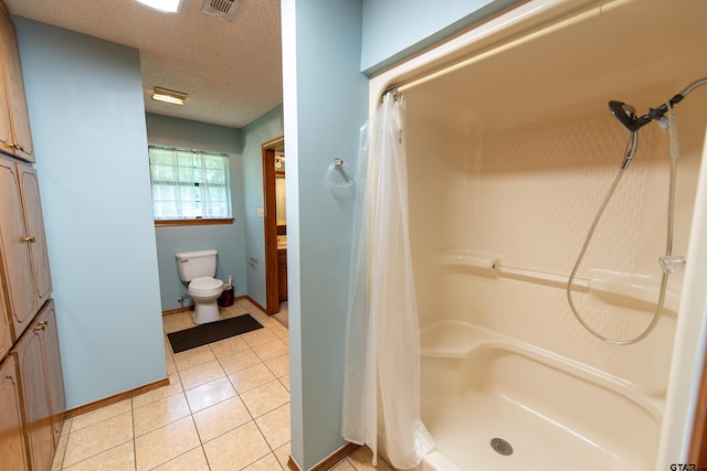 bathroom with a shower with curtain, vanity, a textured ceiling, tile patterned flooring, and toilet