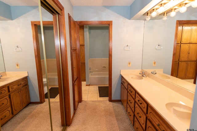 bathroom featuring a washtub, vanity, a textured ceiling, and tile patterned floors