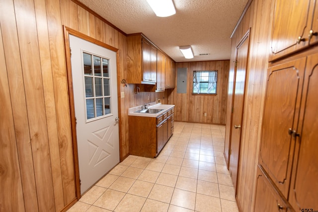 kitchen with a textured ceiling, wood walls, and light tile patterned floors